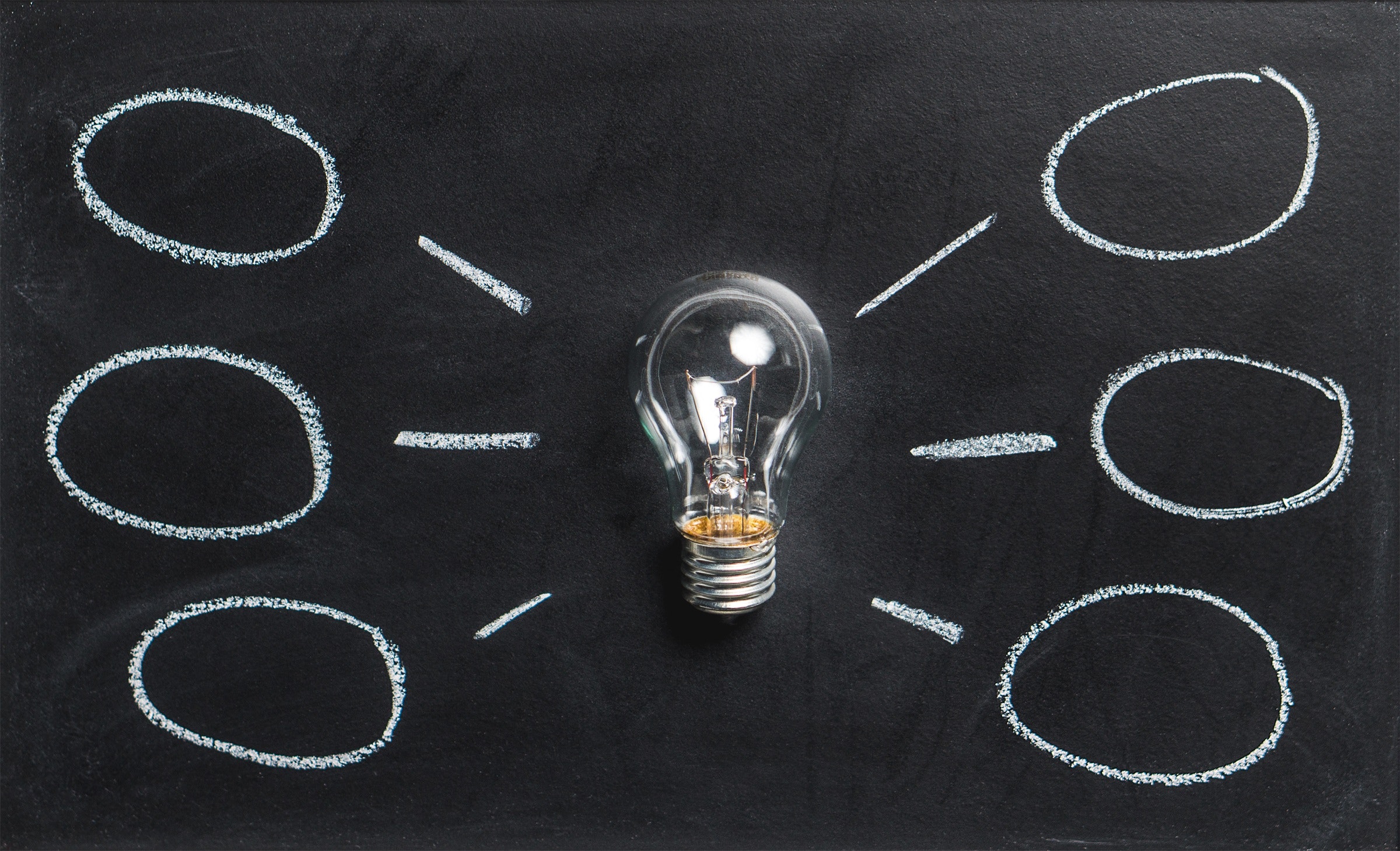 Clear light bulb on black chalkboard